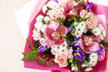 Anneler günü, kadınlar günü ya da doğum günü geçmişi. Çiçek açan orkideler, karanfiller, irisler ve açık pembe arka planda bahar yeşilliği. Boşluğu kopyala.