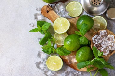 Soğuk yaz Mojito kokteyli yapmak. Nane, kireç, buz malzemesi ve taş ya da beton bir masa üzerindeki bar aletleri. En üstteki düz yerde. Boşluğu kopyala.
