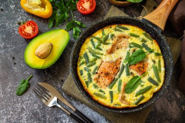 Kahvaltı ya da öğle yemeği konsepti. Köy usulü omlet (omlet, omlet), somon filetosu ve yeşil fasulye ile birlikte taştan bir arka planda tavada.. 