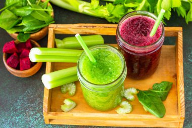 Vejetaryen içecekler, vejetaryen diyeti, beslenme, sağlıklı detoks kavramları. Pancar püresi ve yeşil smoothie kereviz ve taştan bir arka planda ıspanak.