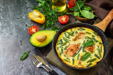 Kahvaltı ya da öğle yemeği konsepti. Köy usulü omlet (omlet, omlet), somon filetosu ve yeşil fasulye ile birlikte taştan bir arka planda kızartma tavasında. Boşluğu kopyala.