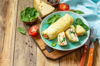 Japon mutfağı. Kahvaltıda ulusal Japon yemeği omlet tamago yaki. Tahta bir masada ıspanaklı yumurta, domates ve peynirli sandviç. Boşluğu kopyala.