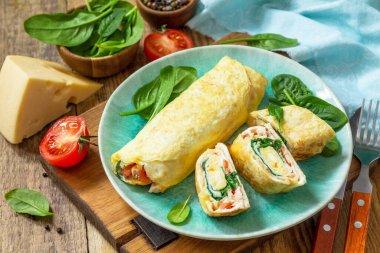 Japon mutfağı. Kahvaltıda ulusal Japon yemeği omlet tamago yaki. Tahta masada ıspanaklı, domatesli ve peynirli yumurta..