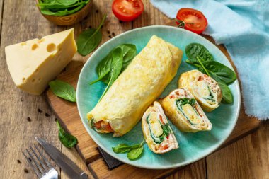 Japon mutfağı. Kahvaltıda ulusal Japon yemeği omlet tamago yaki. Tahta masada ıspanaklı, domatesli ve peynirli yumurta..