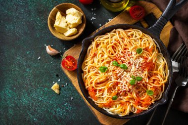 Klasik ev yapımı İtalyan makarnası domates soslu, parmesan peynirli ve fesleğenli. Üst manzara, düz arkaplan. Boşluğu kopyala.
