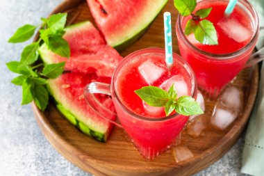 Soğuk yaz içeceği. Bardaklarda taze karpuz içeceği ve taş bir masanın üstünde karpuz dilimleri.. 