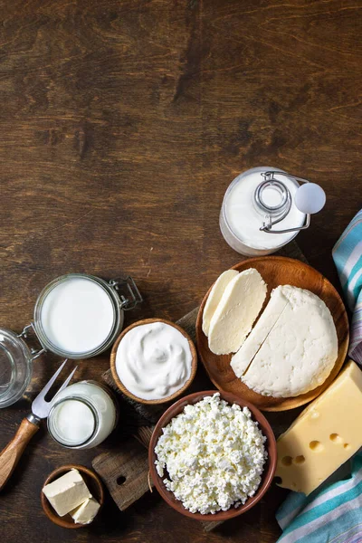 Set of different dairy organic products (milk, sour cream, cottage cheese, yogurt and butter) on a rustic wooden countertop. Top view flat lay. Copy space.