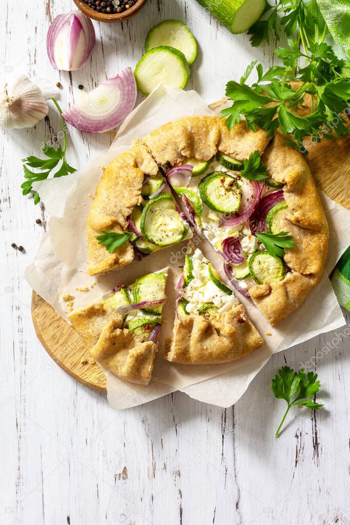 Healthy rye flour baked goods, gluten free, diet food. Galette with zucchini, onions and feta cheese on a wooden table. Top view flat lay background. Copy space.