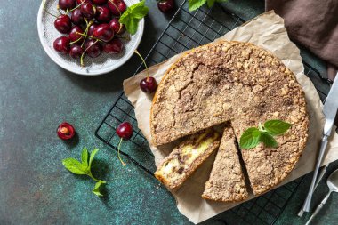 Süzme peynirli köylü turtası. Süzme peynirli kek, kiraz ve çırılçıplak taş bir tezgahın üstünde. Üst görünüm düz arkaplan.