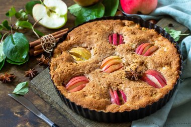 Elma pişirme glütensiz mevsim. Elmalı sonbahar pastası, fındık ve ahşap bir masada tarçın.. 