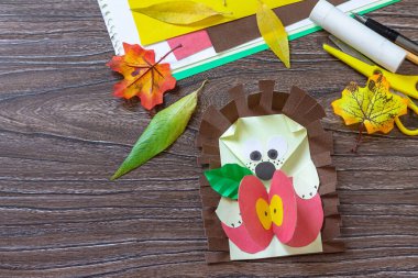 Ahşap bir masada elmalı bir sonbahar tebrik kartı kirpisi. El yapımı. Çocukların yaratıcılığı projesi, el işleri, çocuklar için el sanatları.