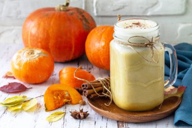 Sonbahar içkisi. Balkabağı aromalı latte ya da kırsal ahşap bir masada bardak içinde kahve.. 