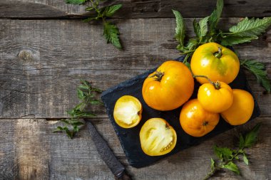Mutfak ahşap masasında taze, taze, olgun organik sarı domatesler. Diyet menüsü ve hasat konsepti. Üst görünüm düz arkaplan. Boşluğu kopyala.