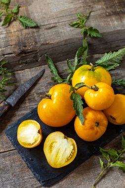 Mutfak ahşap masasında taze, taze, olgun organik sarı domatesler. Diyet menüsü ve hasat konsepti. Boşluğu kopyala.