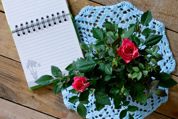 Rosas en servilleta de punto azul y almohadilla para escribir — Foto de Stock