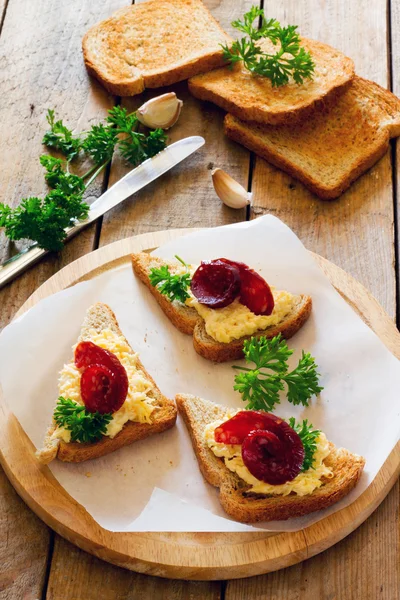 Bruschetta se sýrem, česnekem a strhl klobása na papíře — Stock fotografie