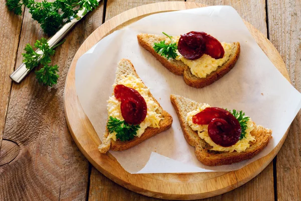 Bruschetta with cheese, garlic and jerked sausage on paper — Stock Image Bruschetta with cheese, garlic and jerked sausage on paper Stock Photo
