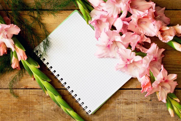 Kwiaty różowe gladioluses i notebook — Zdjęcie stockowe