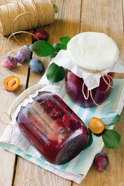 Ameixa enlatada latas de suco de ameixa em uma mesa de madeira — Fotografia de Stock