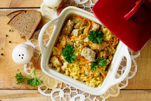 Pilaf con carne en una olla sobre una mesa de madera, vista superior — Foto de Stock