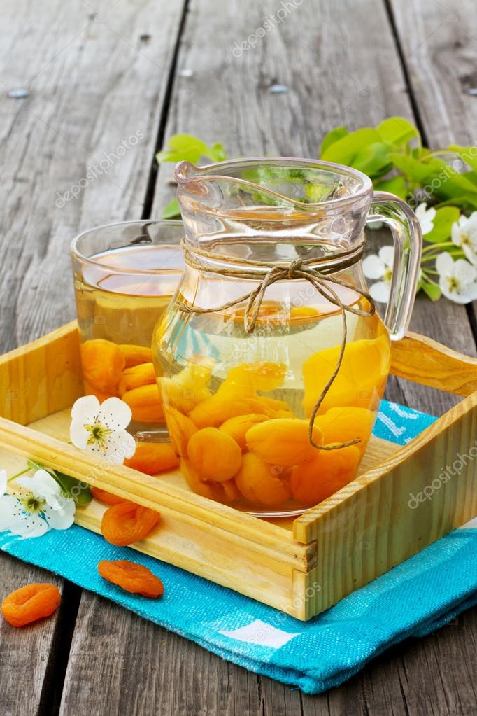 Sweet compote of dried apricots in a jar on a wooden background Stock