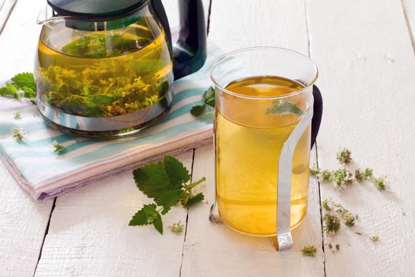 Konvice a šálek bylinného čaje s čerstvou mátou květina na dřevěné — Stock fotografie