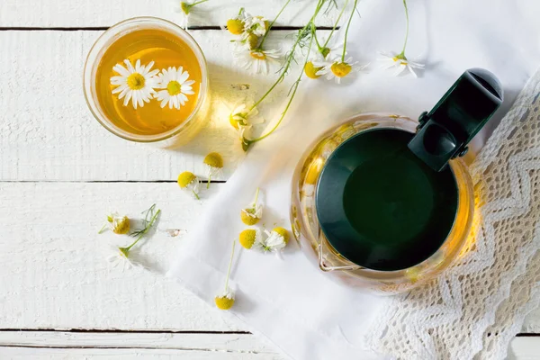 Konvice a šálek bylinného čaje s květy heřmánku, pohled shora — Stock fotografie