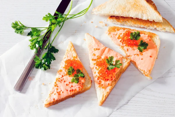 Tostadas con mantequilla y caviar de salmón sobre fondo de madera —  Fotos de Stock