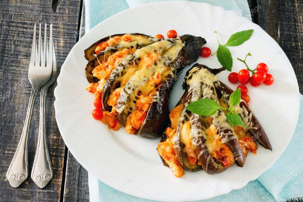 Baked eggplant with cheese, tomatoes and chicken on a dark woode