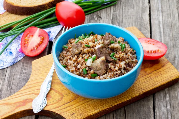 Alforfón con carne y tomates sobre fondo de madera — Foto de Stock