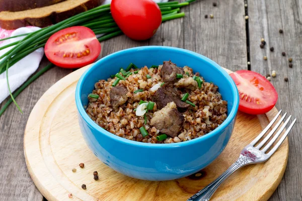 Alforfón con carne y tomates sobre fondo de madera — Foto de Stock