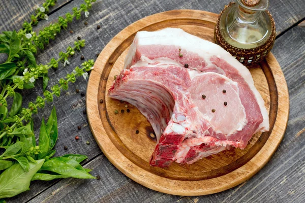 Carne cruda costillas filete de hueso, cerdo con albahaca y mantequilla en una cuttin —  Fotos de Stock