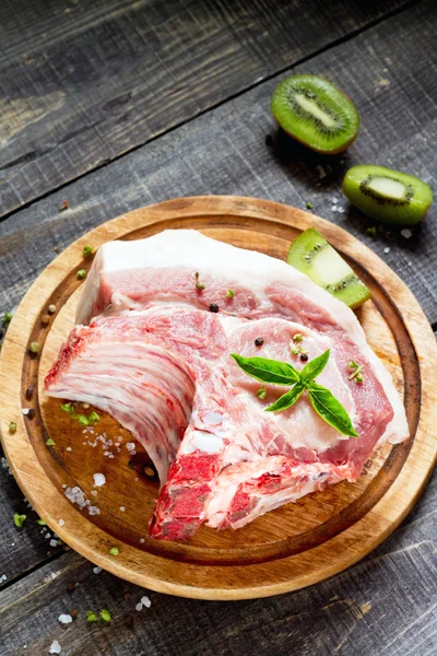 Carne cruda costillas filete de hueso, cerdo con albahaca y kiwi fruta en un cu —  Fotos de Stock