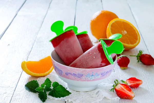 Helado de fresa paleta naranja sobre una mesa blanca — Foto de Stock