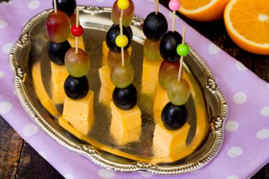 Peynir ve ahşap bir masa üzerinde üzüm ile kanepe