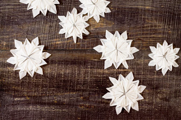 Adornos de origami con copos de nieve en una espalda de madera oscura — Foto de Stock