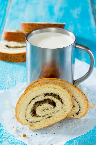 Un pain de pain frais avec des graines de pavot et une tasse de lait sur la languette — Photo