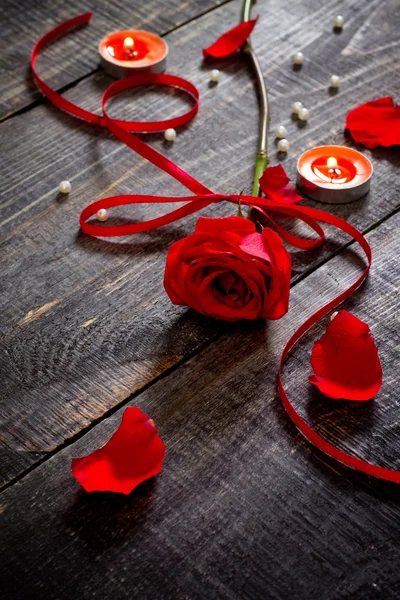 Rosa rossa con nastro rosso e candela su sfondo scuro — Foto Stock