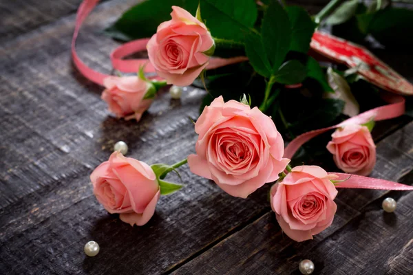Belle rose rosa su un tavolo di legno scuro con un nastro rosa — Foto Stock