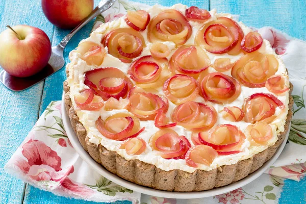Яблочный пирог со сливочными розами на деревянном столе — стоковое фото