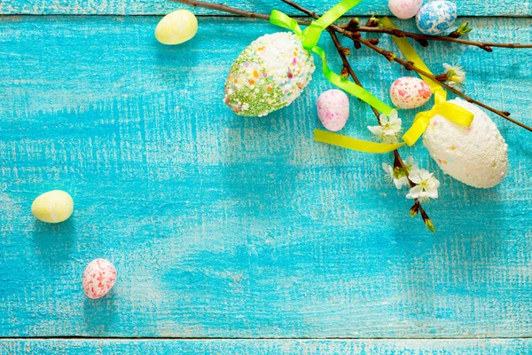 Ovos de Páscoa coloridos e ramo de cereja em um fundo azul — Fotografia de Stock