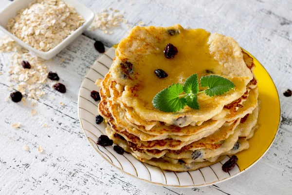 Oatmeal Pancakes with honey and raisins on a rustic table — Stock Photo, Image