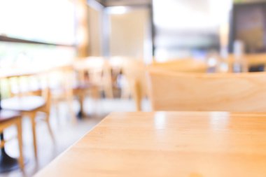 Sabah ışığında montaj ürünü sergisi için seçici bir şekilde ahşap sehpaya odaklanmış modern kahve dükkanı.