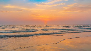 Denizde günbatımının güzel sakinliği. Yansıma plajında insanlar yok. Güneş ışığı ve gökyüzünün renkli gölgesi.