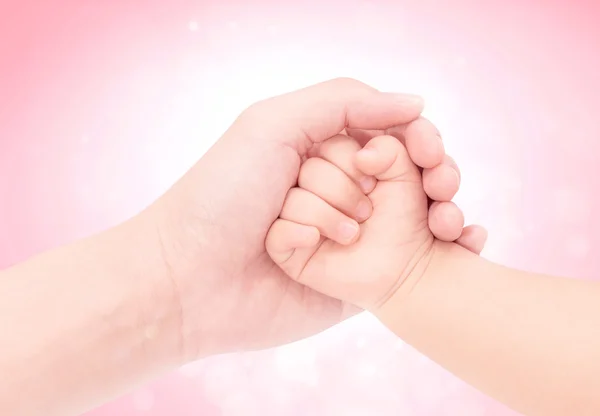 Mão do bebê na mão do amor com fundo de brilho rosa — Fotografia de Stock