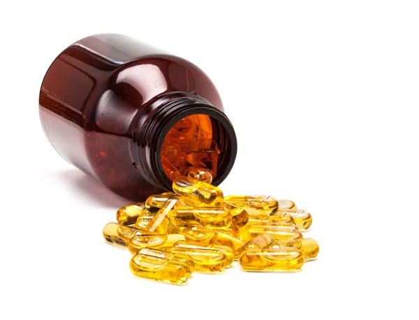 Fish oil capsules spilling out from brown glass bottle — Stock Photo, Image