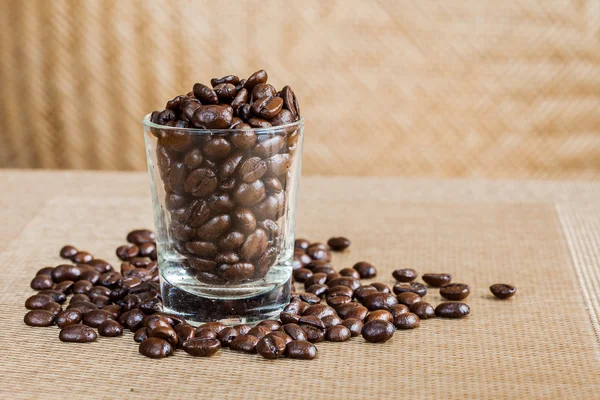 Coffee beans in glass shot with weave background — Stock Photo, Image