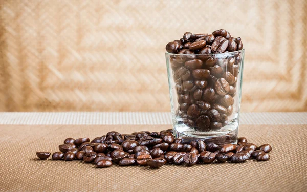 Coffee beans in glass shot with weave background — Stock Photo, Image