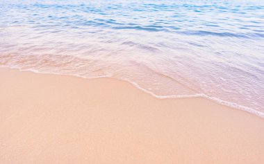 Yumuşak mavi okyanus dalgaları el değmemiş tropikal kumlu bir plaja nazikçe vuruyor. Yaz tatili için mükemmel.