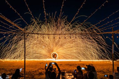 Koh Samet, Rayong, Tayland-2025 Aralık 19: Turistler bir gece etkinliği sırasında plajda olağanüstü bir yangın dönüşü performansı izleyip kaydettiler.